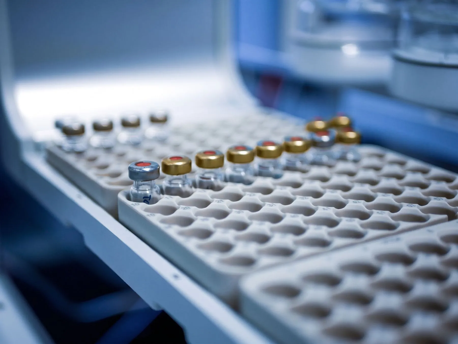 Glass sample vials with crimp caps in an analysis tray inside a laboratory instrument